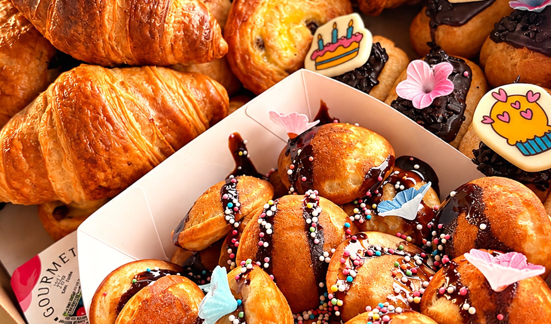 Cateringbox met croissants, chocoladebroodjes en poffertjes met feestelijke decoratie